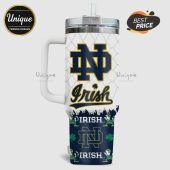 White tumbler with a handle, clear lid and straw, featuring a Notre Dame 'ND' logo and 'Irish' text, repeated pattern with shamrocks and leprechauns.!