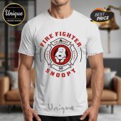 White tee with cartoon firefighter badge design in red ink. Features Snoopy. Reads: Firefighter, Fire Dept, Snoopy, Always Ready!