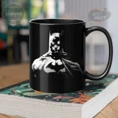 Black coffee mug with a white and gray gritty comic book style Batman graphic, showing the superhero with cape and bat symbol!