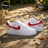 Custom white sneakers with red swoosh, Eslabon Armado text, Amor Nocturno print, and signature graphics on outdoor stone.!