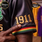 Black satin shirt with gold 1911 embroidery and red, yellow, and green striped sleeve trim!