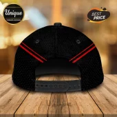 Back view of a black baseball cap with red dual stripes and a plastic adjustable snapback closure on a wood surface.!