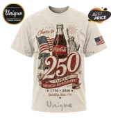 Cream-colored t-shirt featuring a Coca-Cola bottle, Statue of Liberty, Liberty Bell, and 250 years graphic in red and blue.!