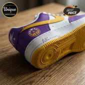 Nike Air Force 1 sneaker with purple and white leather, yellow swoosh, yellow sole, and Los Angeles basketball emblem.!