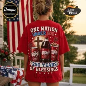 Red graphic t-shirt featuring Dr. Pepper cans, a cross, fireworks, and text reading One Nation Under God 250 Years.!