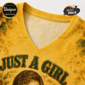 Yellow V-neck t-shirt with sunflower pattern and green text reading JUST A GIRL featuring a partial portrait print.!