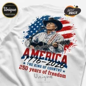 White t-shirt featuring a cowboy singer, American flag splash, and text reading America 1776-2026 The King of Country.!