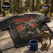 Black acid-wash Godzilla 1954 graphic t-shirt featuring a Japanese monster illustration and red text on a wooden table.!