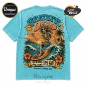 Light blue t-shirt featuring a Grateful Dead skeleton surfing, tropical palm trees, hibiscus flowers, and sunset artwork.!
