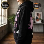 Black cotton hoodie featuring pink butterfly graphics, light pink lettering, and star icons on a woman in a room.!