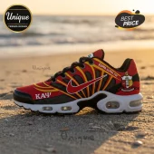 Kappa Alpha Psi branded running shoe with red, gold, and black panels, white sole, and Greek lettering on a sandy beach.!