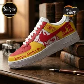 Kappa Alpha Psi custom sneaker in crimson and cream with Greek letters and logos on a wooden desk with vintage books.!