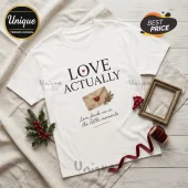 White crew neck t-shirt with Love Actually text, a watercolor envelope icon, and the quote Love finds us in the moments.!