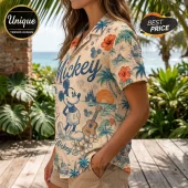 Woman wearing a beige tropical button-down shirt featuring Mickey Mouse, palm trees, hibiscus flowers, and a ukulele print.!