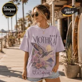 Lavender vintage-wash cotton t-shirt with Mothra graphic, hibiscus flowers, and Japanese text on a wooden boardwalk.!