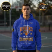 Man wearing a blue New York Knicks NBA Champions 2025-26 hoodie with white drawstrings and orange and gold screen printing.!
