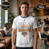 Man wearing a white New York Knicks 2026 NBA Champs graphic t-shirt with blue collar trim in a cafe setting.!