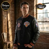 Man wearing black varsity jacket with orange and blue New York Knicks basketball logos and NBA sleeve patch.!