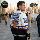 Man wearing a New York Knicks 2026 NBA Finals Champions white and black varsity jacket with orange and blue accents.!