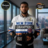 Man wearing white and black New York Knicks varsity jacket with Champions text, team logos, and city skyline graphics.!