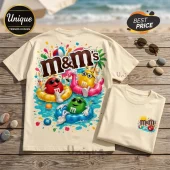 Cream colored cotton t-shirt featuring M&M characters wearing sunglasses and floating in a pool with a beach ball background.!