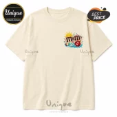 Cream colored cotton t-shirt with small M&Ms brand logo graphic on chest featuring a red candy character at the beach.!