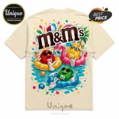 Cream colored t-shirt featuring M&M characters swimming in a pool with inflatable rings and colorful summer graphics.!