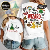 White t-shirt featuring Wizard of Oz graphics, including ruby slippers, yellow brick road, and text I have a WIZARD addiction.!