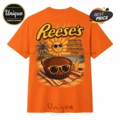 Orange graphic t-shirt featuring a Reese's logo, a sun with sunglasses, a beach scene, and a peanut butter cup icon.!