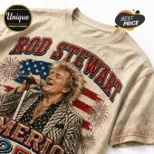 Beige graphic t-shirt featuring Rod Stewart singing, American flag background, fireworks, and vintage style text.!