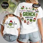 White t-shirts featuring Grinch graphics, holiday icons, and text reading I have a GRINCH addiction and Merry Grinchmas.!