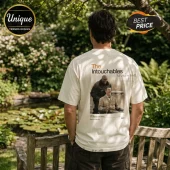 Man wearing an off-white cotton t-shirt with a graphic of the film The Intouchables on the back, standing in a garden.!