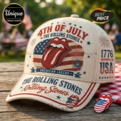 Cream baseball cap featuring The Rolling Stones tongue logo, US flag, fireworks, and 4th of July text on a wooden table.!