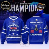 Blue Toronto Marlies 2026 Calder Cup Champions sweatshirt with trophy, hockey sticks, and white leaf emblem graphics.!