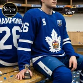 Blue hockey jersey with white maple leaf and crown logo, number 26, worn by a player sitting in a wooden locker room.!
