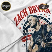 White graphic t-shirt featuring a vintage-style sketch of Zach Bryan playing acoustic guitar with red and blue stars.!