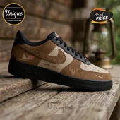 Custom brown and tan Nike Air Force 1 sneaker featuring deer head icons, Adelaide branding, and script text on wood table.!