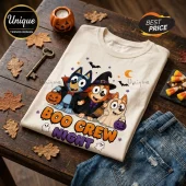 Bluey Boo Crew Halloween T-Shirt on a wooden table with cartoon characters wearing vampire and witch costumes and a ghost.