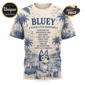 Bluey Playful Adventures Special Edition T-Shirt with blue palm tree print, character illustration, and text on tan fabric.