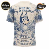 Bluey Playful Adventures Special Edition T-Shirt with blue line art of Bluey, palm trees, and home on a beige background.