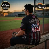 Man wearing a personalized black baseball jersey with American flag patterns on the numbers and shirt fabric on a field.!