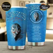 Eagles band 50th anniversary blue stainless steel tumbler featuring skull art and a tracklist on a wooden table.!