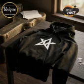 Black cotton hoodie featuring a white geometric star logo, laid on a dark wooden table near a guitar case.!