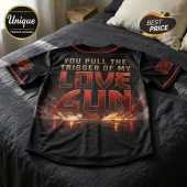 Black baseball jersey featuring KISS Love Gun graphics, red trim, and metallic text on a grey bedspread.!