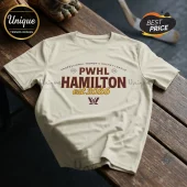 PWHL Hamilton Est 2026 Off-White T-Shirt featuring brown and gold team typography on a textured wooden bench background.