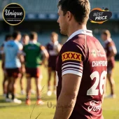 Rugby player wearing maroon jersey with XXXX logo and number 26 on back, standing on a grass field near other players.!