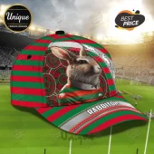 South Sydney Rabbitohs Red Green Mascot Cap with rabbit graphic, striped pattern, and team text on a stadium background.
