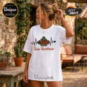 Woman wearing a white t-shirt with a Texas Roadhouse logo, heartbeat graphic, and brown cursive text.!