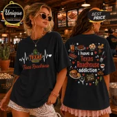Black t-shirt featuring front Texas Roadhouse logo heartbeat graphic and back print displaying steakhouse menu food icons.!