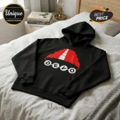Black cotton hoodie featuring a red Devo energy dome hat graphic and the white text DEVO on a white bedspread.!